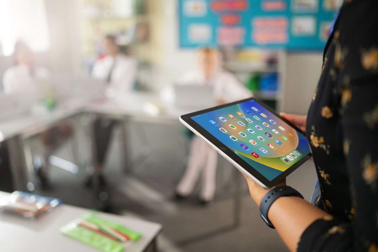 220824_EDU-K12Library-London_MJ_w001250_ALT-DEDE Eine Gruppe von vier Schülern und Schülerinnen sitzt mit einem iPad vor einer Schrankwand.