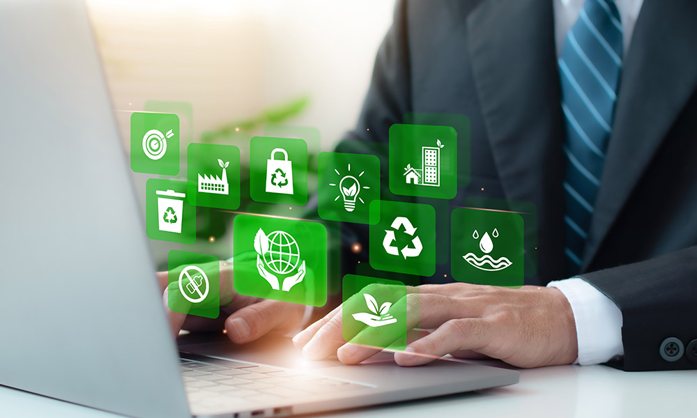 Illustratives Bild: Person sitzt vor einem Laptop. Über dem Laptop sind weiße Symbole auf grünem Hintergrund eingeblendet, die Nachhaltigkeit und Recycling darstellen.