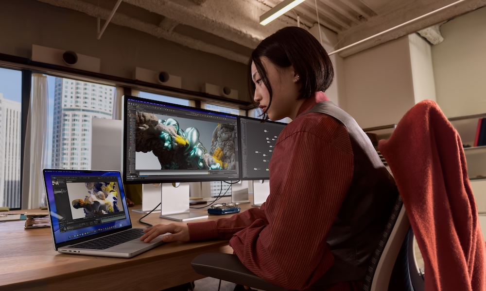 Ein Mann sitzt vor einem Laptop und hält in der Hand einen Zettel, während er tippt.